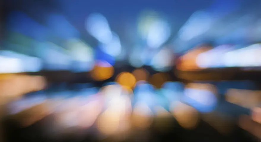 Luci sfocate di una città di notte, come se vedo sfocato da un occhio. Colori blu, arancioni e bianchi si fondono in un effetto astratto.