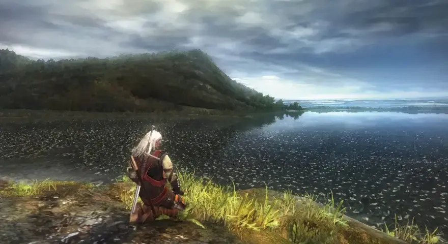 Geralt klęczy nad jeziorem, wpatrując się w horyzont. Wizualizacje z wiedzmin 1 remake zapierają dech w piersiach.