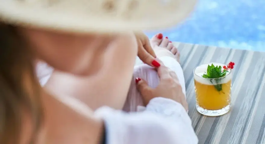 Relaks przy basenie z drinkiem w hotelu dla dorosłych Polska. Kobieta w słomkowym kapeluszu odpoczywa na leżaku.