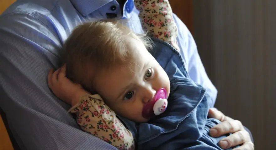 En pappa håller sin lilla dotter, som har en napp i munnen. Bilden känns som en dikt till min dotter.