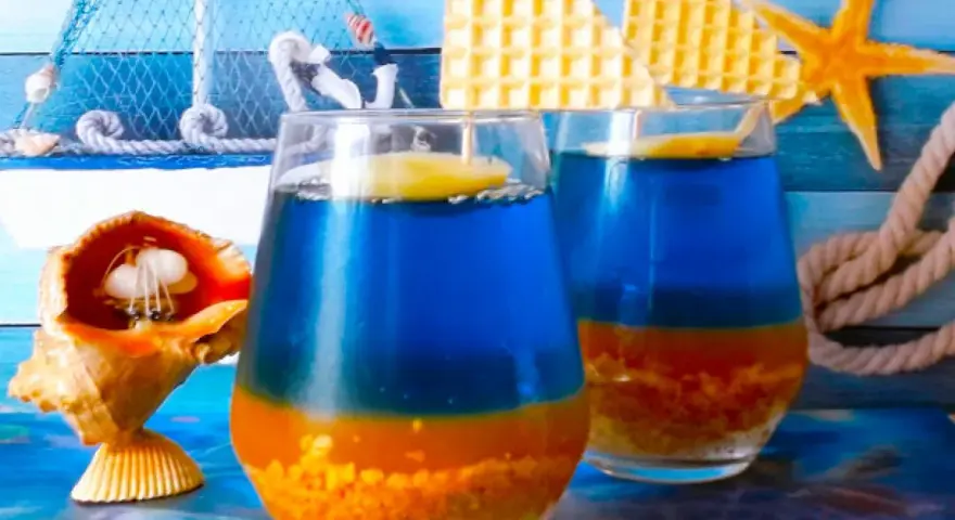 Dwa orzeźwiające drinki Błękitna Laguna, ozdobione plasterkiem cytryny, na tle morskich dekoracji.