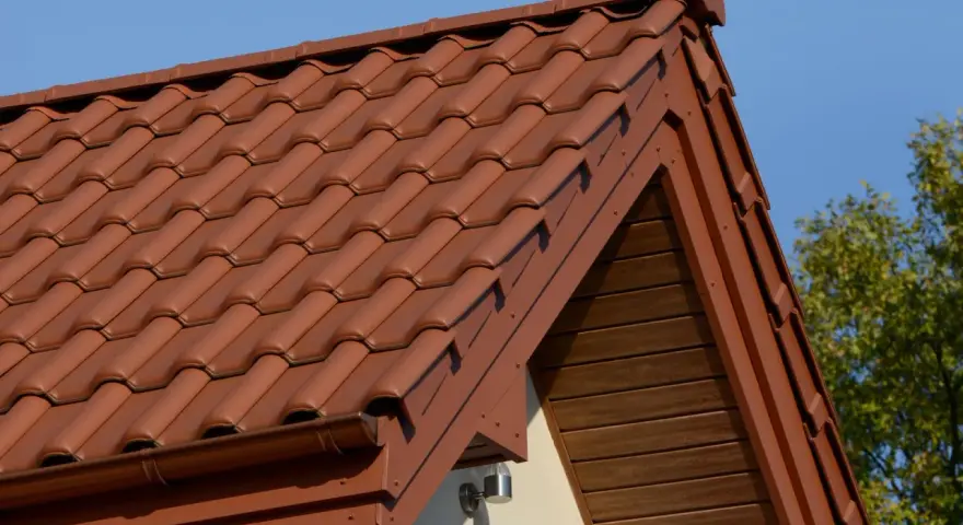Brązowa, lekka konstrukcja dachu z dachówki ceramicznej, z widocznym okapem i drewnianą podbitką.
