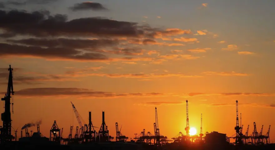 Silhouetten von Kränen im Hamburger Hafen bei Sonnenuntergang. Perfekt für die Pfingstferien in Hamburg.