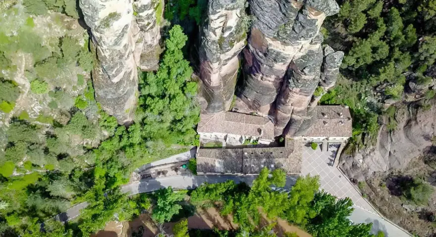 Vista aérea del **barranco de la Hoz, Guadalajara**, con edificios integrados en las rocas y vegetación exuberante.