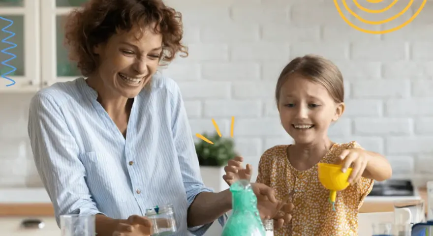 Mama i córka śmieją się, wykonując spektakularne eksperymenty dla dzieci z zieloną pianą w probówce.