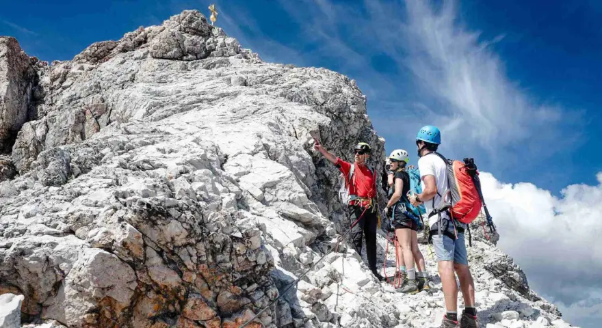 Bergsteiger am Gipfel der Zugspitze ohne Klettersteig. Ein Führer erklärt den Weg.