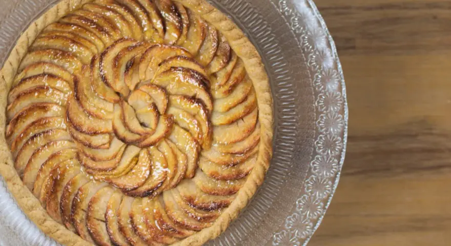 Tarte aux pommes dorée sur un plat en verre, parfaite pour une recette gâteau avec pâte feuilletée facile.
