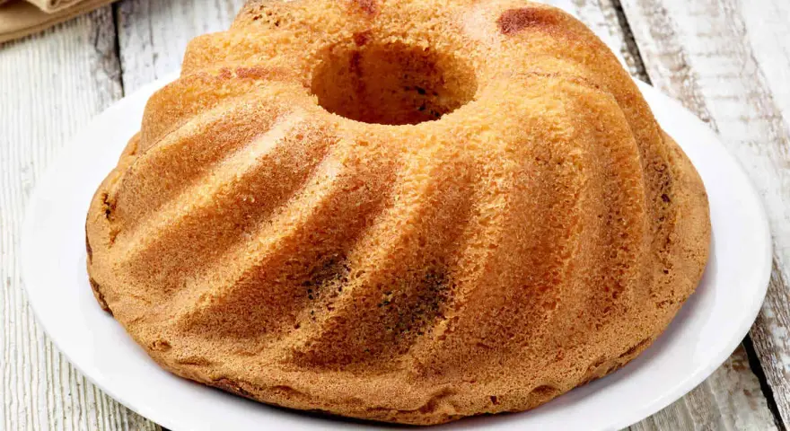 Ciambellone senza uova dorato e soffice, con la sua forma a ciambella, pronto per essere gustato.