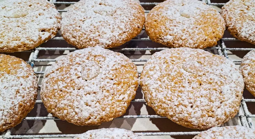 Deliziosi biscotti con farina di mandorle, cosparsi di zucchero a velo, riposano su una griglia.