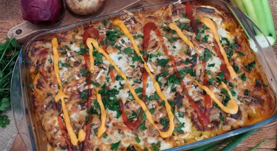 Pyszna keto zapiekanka z mięsem mielonym i cukinią, polana ketchupem i musztardą, posypana natką pietruszki.