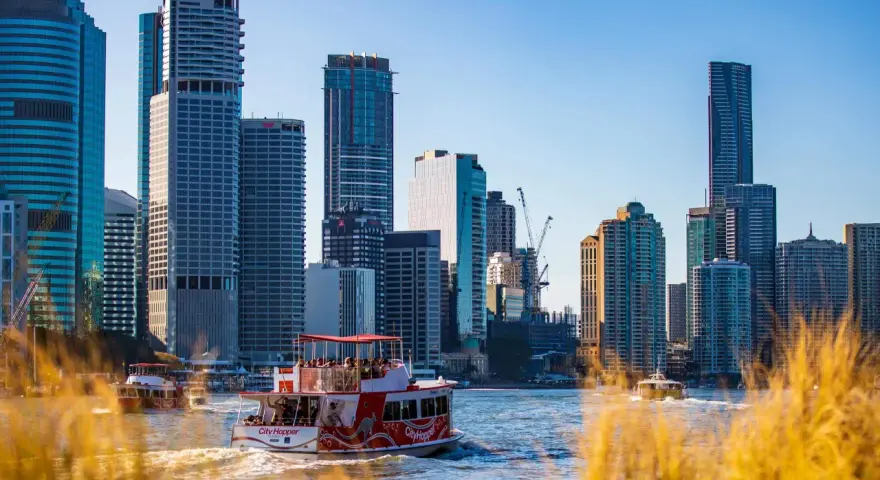 Ein Auslandssemester in Australien: Boote auf dem Fluss vor der Skyline von Brisbane mit modernen Hochhäusern.