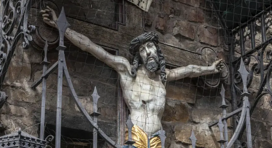 Kreuzigungsgruppe mit Jesus, der die Frage aufwirft, wie alt war Jesus als er starb. Davor ein schmiedeeiserner Zaun.