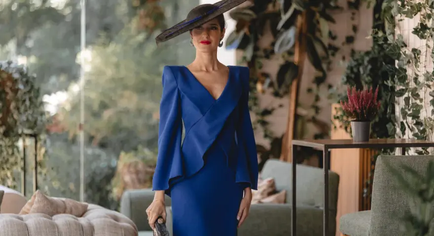 Elegante mujer con vestido azul klein y sombrero, ideal para saber como combinar un vestido azul klein para una boda.