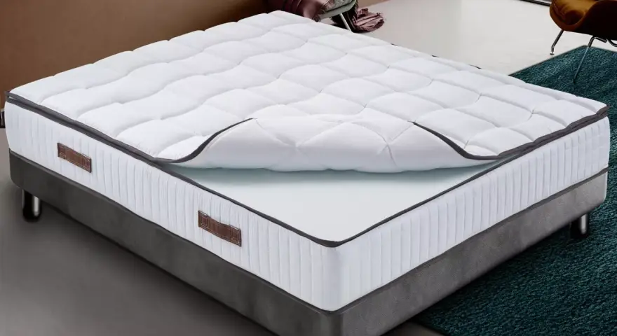 Un matelas king size mémoire de forme, blanc matelassé, sur un sommier gris. Confort garanti pour des nuits paisibles.