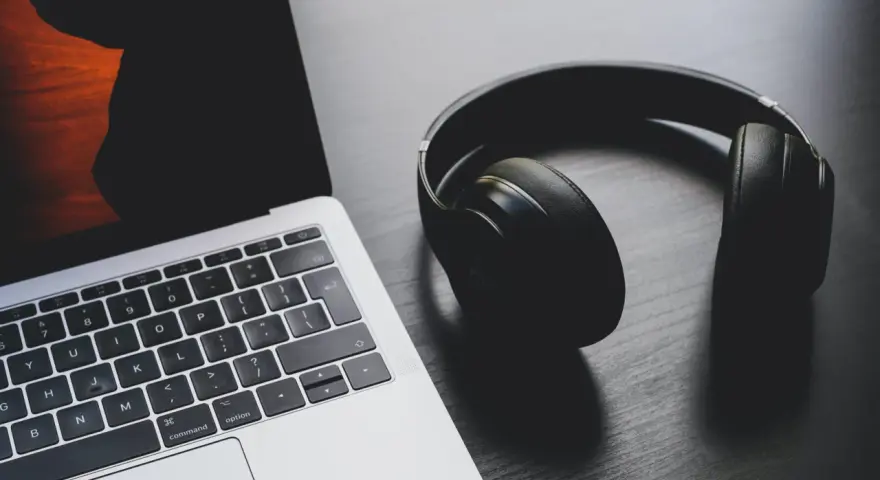Słuchawki leżą obok laptopa. Może to być sygnał, że występuje brak dźwięku w laptopie i potrzebne są słuchawki do słuchania.