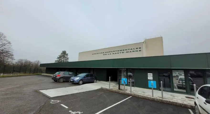 Devant les archives départementales 52, deux voitures sont garées près de l'entrée. Le bâtiment porte l'inscription "ARCHIVES DEPARTEMENTALES DE LA HAUTE-MARNE".