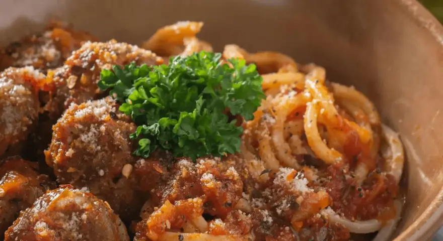 En skål med läckra polpette al sugo, köttbullar i tomatsås, serverade med pasta och toppade med färsk persilja och parmesan.