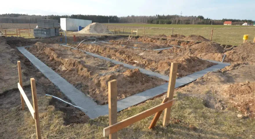 Rozpoczęto wylewanie fundamentu pod nowy dom. Wykopano rowy, w których widać świeży beton.