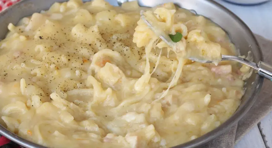 Una padella piena di cremosa pasta con patate, condita con pepe nero. Un piatto confortante e saporito.