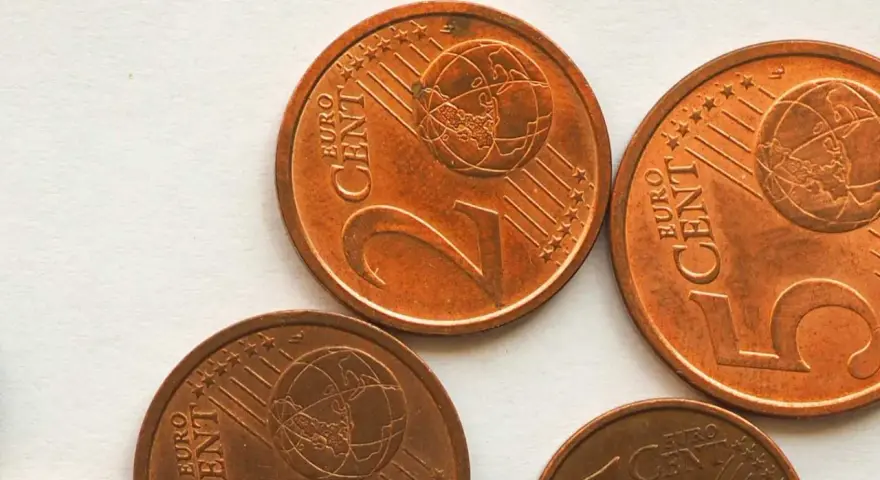 Plusieurs pièces de 2 centimes d'euro, dont une pièce 2 euros rare, sont visibles sur un fond clair.