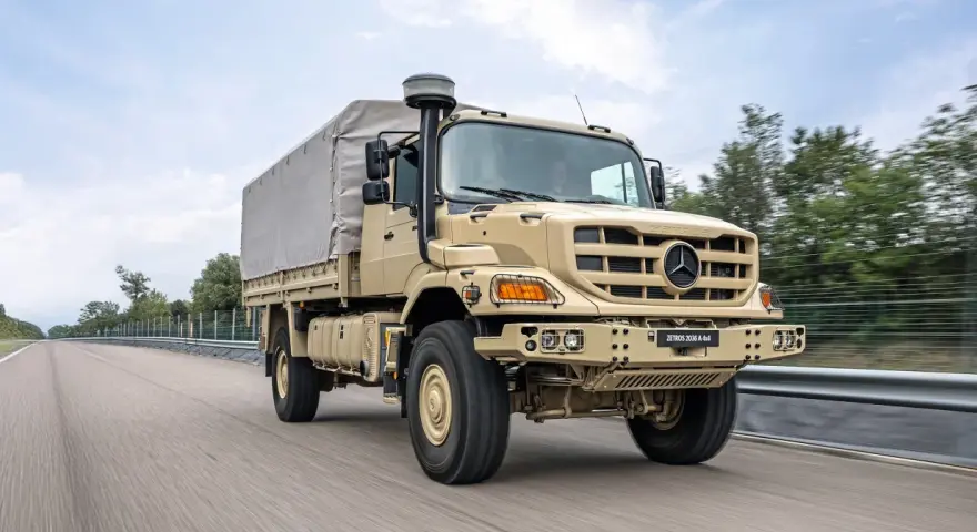 Beżowy Mercedes Zetros 2036 A 4x4 z plandeką jedzie po drodze, gotowy na każde wyzwanie.