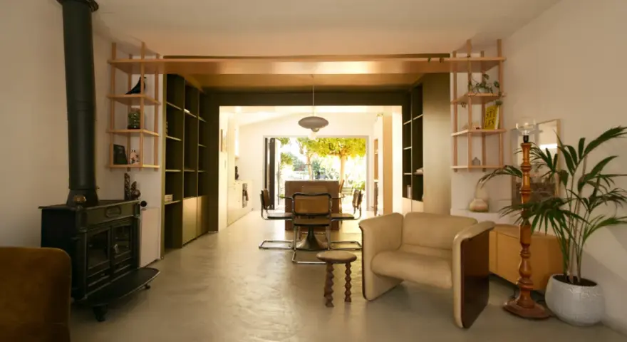 Aménagement maison en longueur : salon avec poêle, étagères et vue sur salle à manger et jardin.