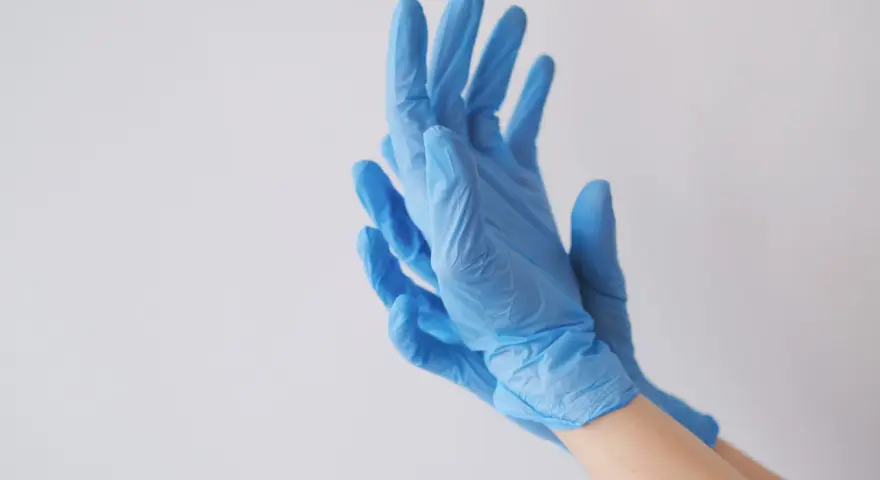 Ręce w niebieskich rękawiczkach nitrylowych, idealnych jako rękawiczki do laboratorium chemicznego.