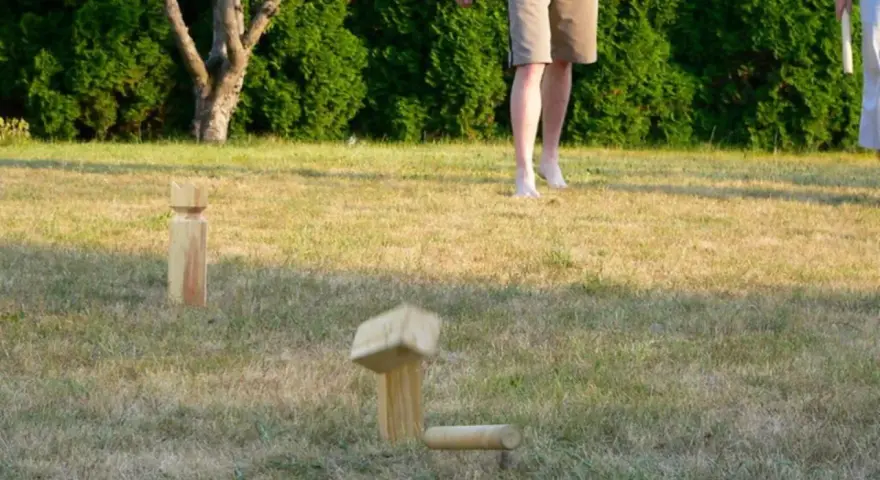 Holzfiguren für Outdoor-Spiele im Gras. Ein Spielstein ist in der Luft, bereit für das nächste Spiel.