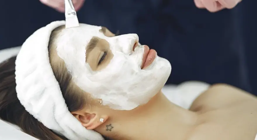 A woman receives a soothing facial mask application. This is a relaxing facial vs massage experience.