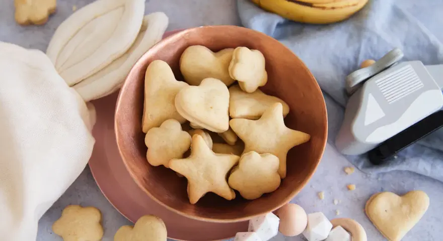 Kleine Sterne und Herzen: Baby Kekse backen ab 6 Monate. Dazu Bananen und ein Holzspielzeug.