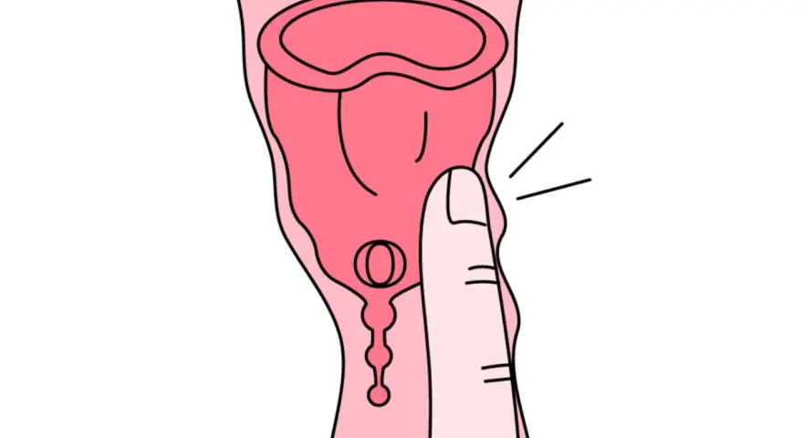 Dłoń naciska na kubeczek menstruacyjny. Tworzywo TPE, choć popularne, może budzić pytania o jego szkodliwość.