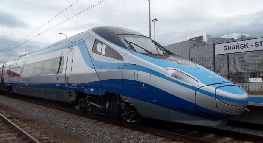 Nowoczesny pociąg Pendolino w kolorach biało-niebieskim stoi na torach przy peronie.