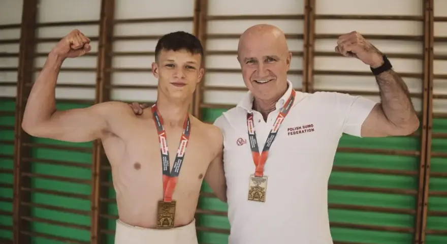 Dwóch zapaśników sumo z medalami, młody zawodnik w tradycyjnym stroju i trener. Prawdopodobnie świętują rekord Polski suma.