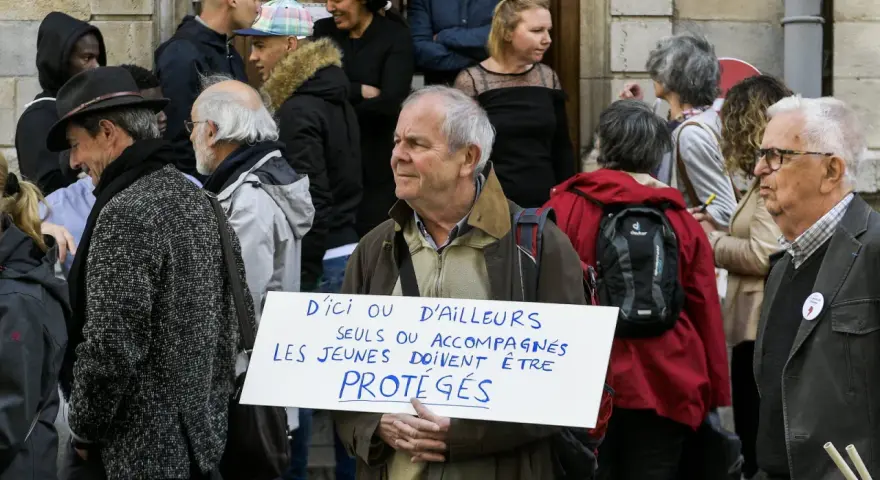 Un homme tient une pancarte "D'ici ou d'ailleurs, seuls ou accompagnés, les jeunes doivent être protégés", soutenant un centre d'accueil pour mineur.