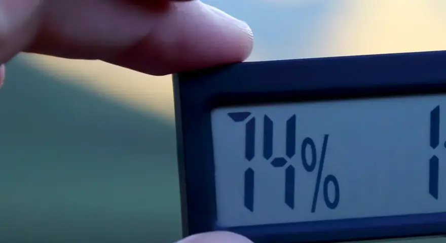 En digital hygrometer visar 74%, vilket indikerar normal luftfuktighet inomhus.