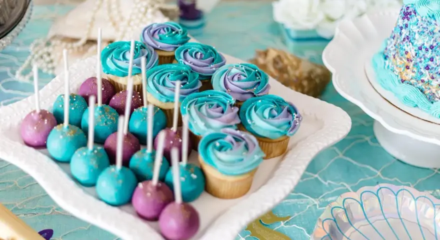Söta cupcakes och cake pops i lila och turkost, perfekta att köpa till babyshower. Havstema med pärlor och snäckskalsformade tallrikar.