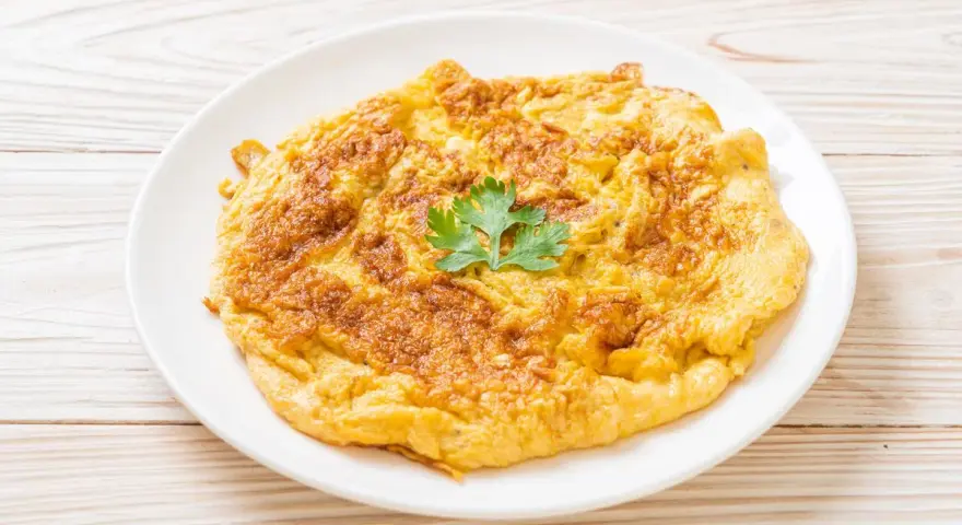 Frittata dorata e soffice, preparata in friggitrice ad aria, guarnita con un ciuffo di prezzemolo fresco.