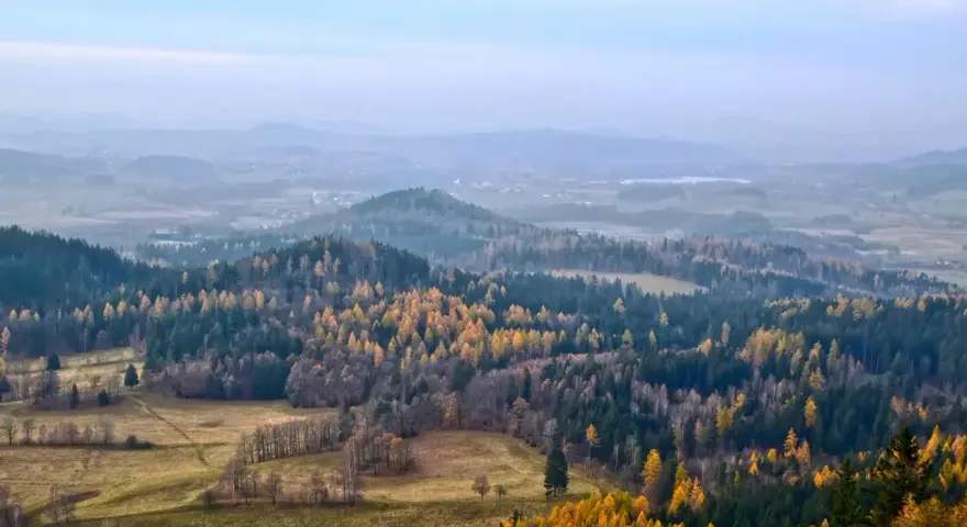 Jesienny krajobraz Gór Izerskich. Złote i zielone lasy, pola i mgliste wzgórza tworzą malownicze szlaki.