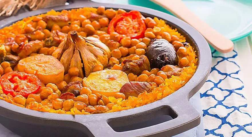 Arroz al horno valenciano con garbanzos, tomate, patata, ajo y morcilla en una paellera.