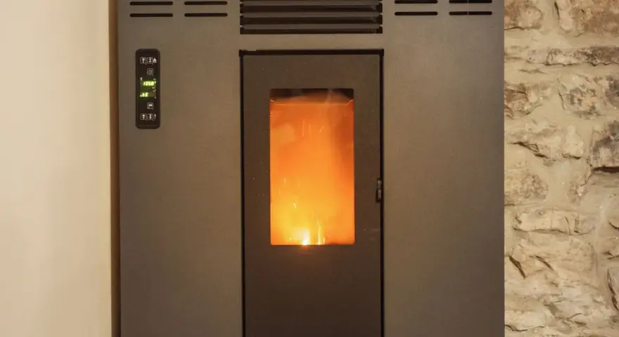 Stufa a pellet con fiamma viva visibile. Il pannello di controllo mostra "19.5°". La distanza candeletta stufa pellet è ottimale per l'accensione.