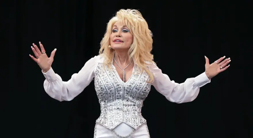 Dolly Parton, strahlend in Weiß, singt auf der Bühne. Sie ist eine Ikone, und ihre Musik ist zeitlos, egal wie alt sie ist.