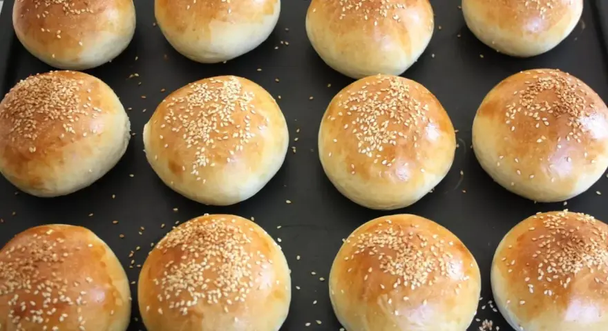 Nybakade frallor med sesamfrön på en plåt, redo att ätas. Perfekt för att baka frallor till frukost eller fika.