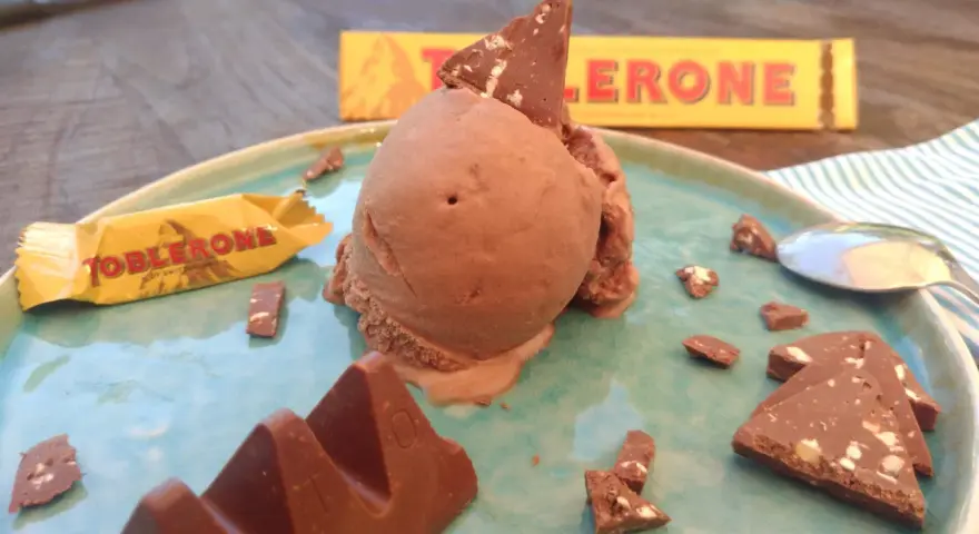 Schokoladeneis mit Toblerone-Stücken und einer ganzen Toblerone-Tafel auf einem Teller.