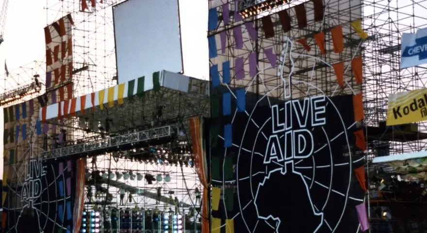 Scena Live Aid w Polsce, ozdobiona kolorowymi flagami i wielkim logo.