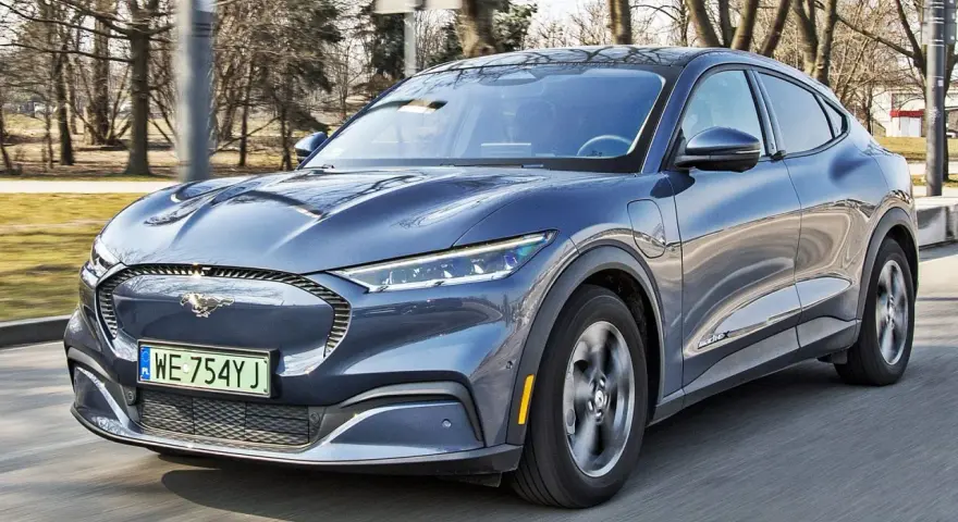 Niebieski Ford Mustang Mach-E w ruchu drogowym, widok z przodu.