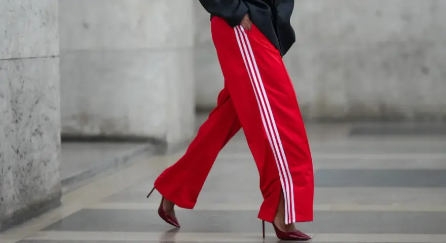 Czerwone spodnie dresowe z białymi lampasami i eleganckie szpilki. Odważne połączenie, które odpowiada na pytanie: jakie buty do dresów?