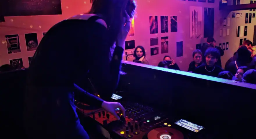 Une dj femme aux platines, ambiançant une foule dans un club.