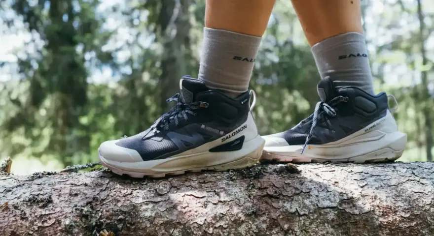 Buty trekkingowe Salomon na pniu drzewa w lesie. Salomon to firma znana z wysokiej jakości obuwia outdoorowego.