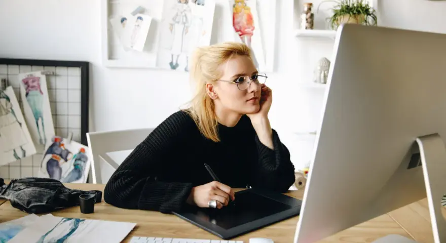 Studentka grafiki komputerowej pracuje przy komputerze, tworząc projekty.