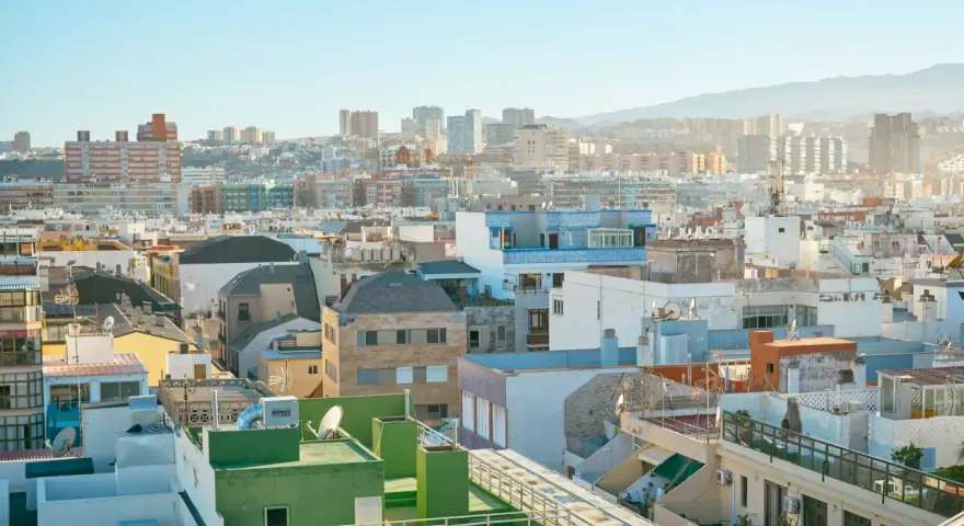 Vista aérea de tejados y edificios de una ciudad española bajo un cielo azul claro.